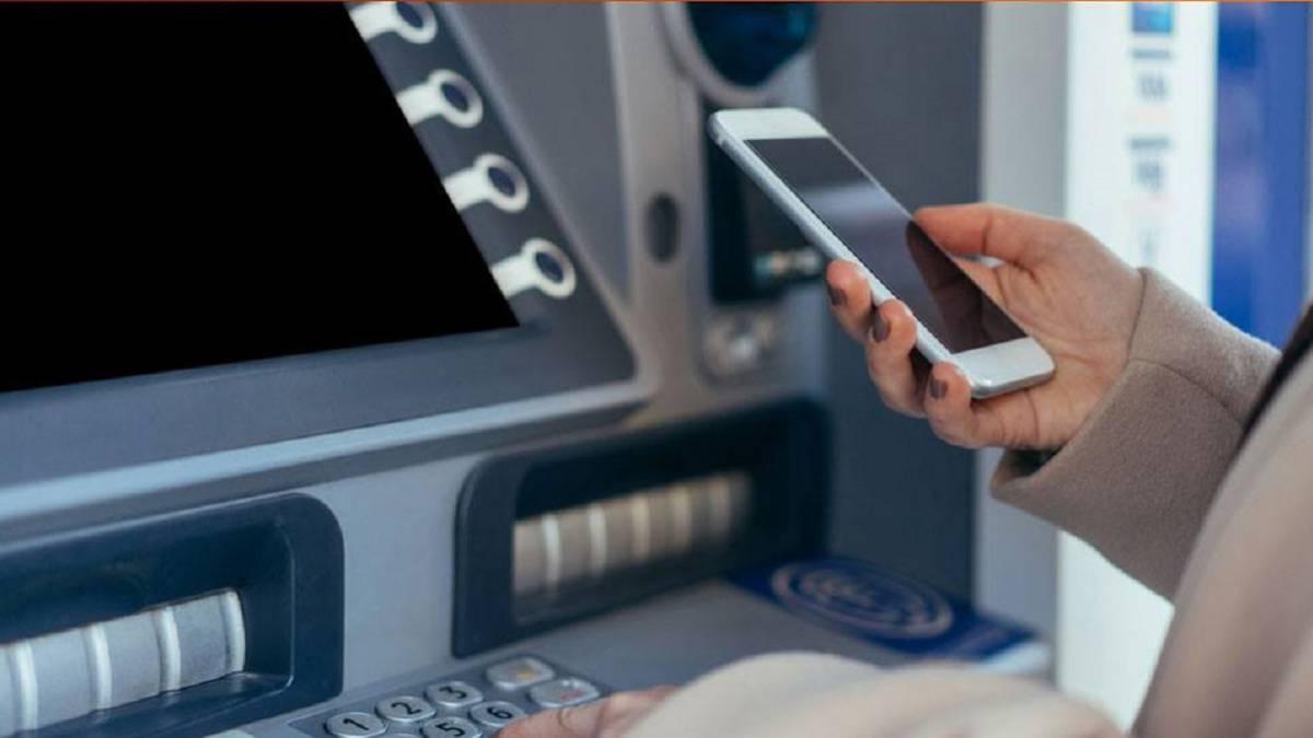 Cajero y celular en mano